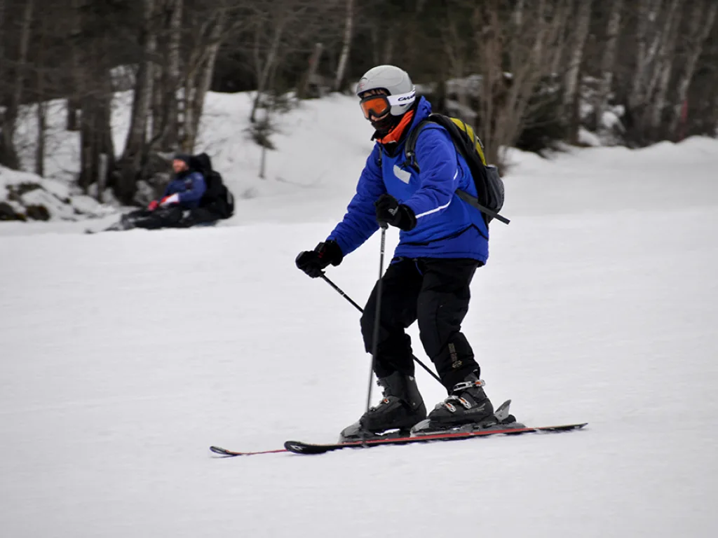 Skifahrer mit Rucksack fährt den Hang hinunter.